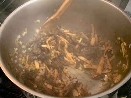 Cooking the mushrooms in the beef mixture.