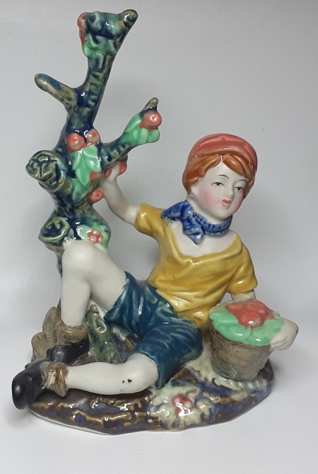 A figurine of a boy beside an orange tree.