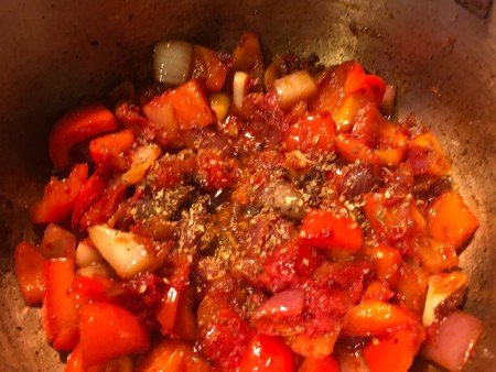 Adding spices to a large soup pot.