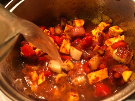 Adding broth to a large soup pot.