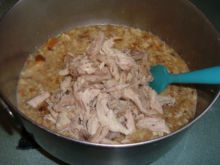Adding chicken to the mixing bowl.