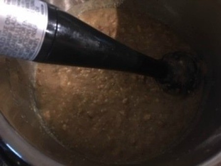 Using an immersion blender in a pot of beans.