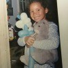 A girl holding a grey stuffed rabbit.