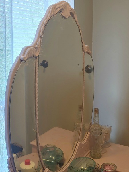 A mirror on a antique vanity.