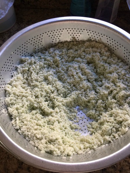 Draining the sticky rice in a colander.