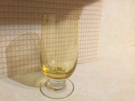 A footed glass with a yellow tint.
