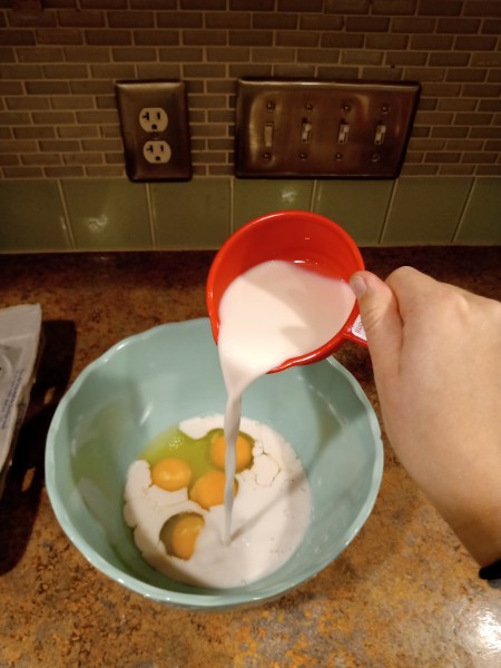 Adding milk to the egg mixture.