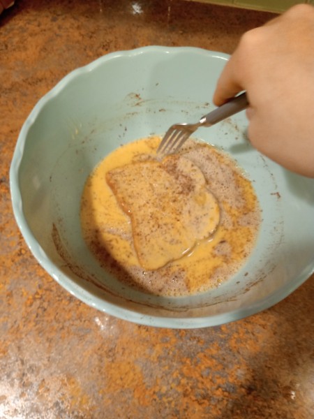 Dipping bread into the egg mixture.