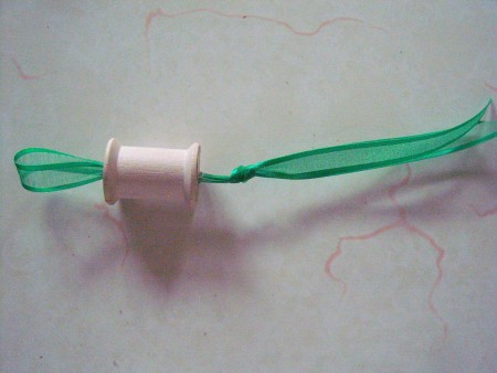 The ribbon is threaded through the spool to allow a place to hang.