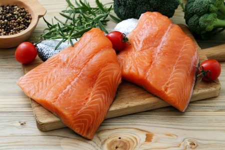 Two salmon fillets on a cutting board.