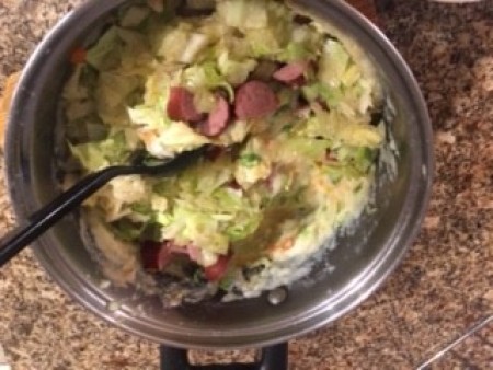 Adding cabbage and sausage to the pot.