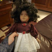 Identifying a Porcelain Doll? - ethnic doll wearing a dress with brown bodice and white lace skirt