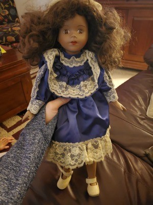 Identifying a Porcelain Doll? - dark skinned doll wearing a blue dress with white lace trim