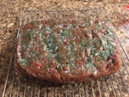 A loaf of cranberry apple banana bread cooling on a rack.