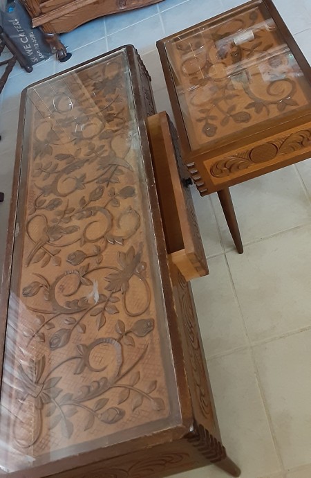 Ornately carved tables with glass surfaces.