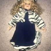 A porcelain doll wearing a coat and hat.