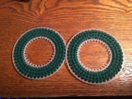 The plastic canvas circles covered in green yarn.