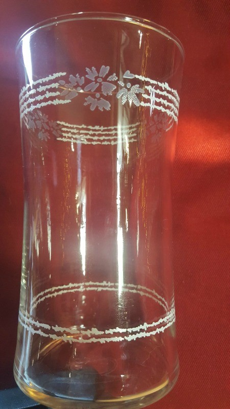 A vintage glass with stripes and flowers at the top.