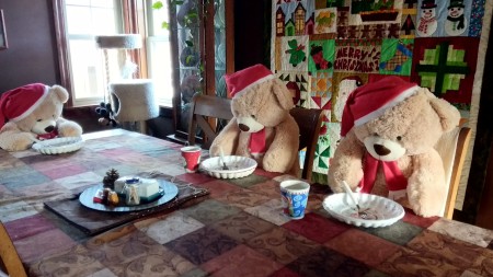 Teddy bears sitting around a table with Christmas decorations.