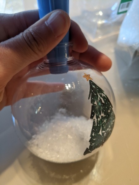 Funnelling fake snow into a clear ornament.