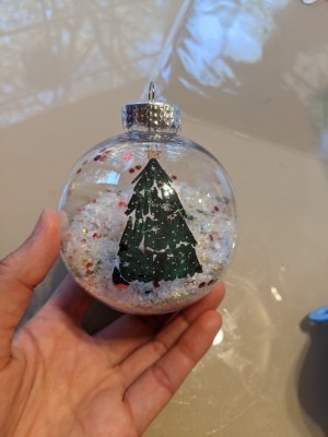 A clear ornament with a Christmas tree decal.