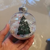 A clear ornament with a Christmas tree decal.