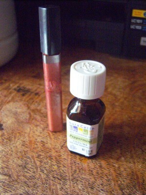 A bottle of peppermint oil next to a lip gloss.