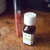 A bottle of peppermint oil next to a lip gloss.