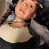 A Native American porcelain doll with a damaged face.