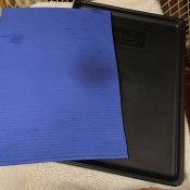 A yoga mat piece lining the inside of a dog crate.