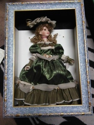 A doll in a shadowbox frame.