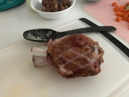 The cooked ham hock on a cutting board.