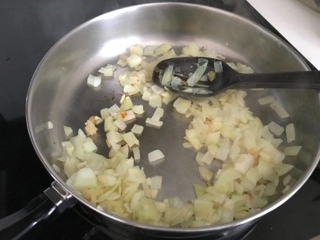 A frying pan with onions cooking.