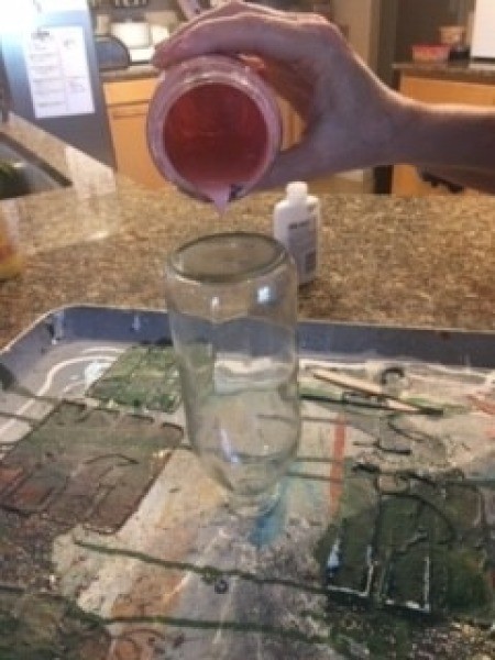 Pouring paint on the bottle.