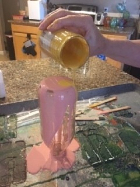 Pouring paint on the bottle.