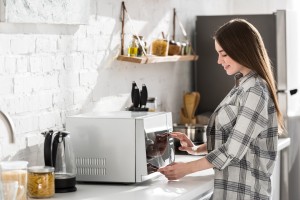 A woman using a microwave.