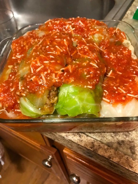 A pan of cabbage rolls covered in tomato sauce.