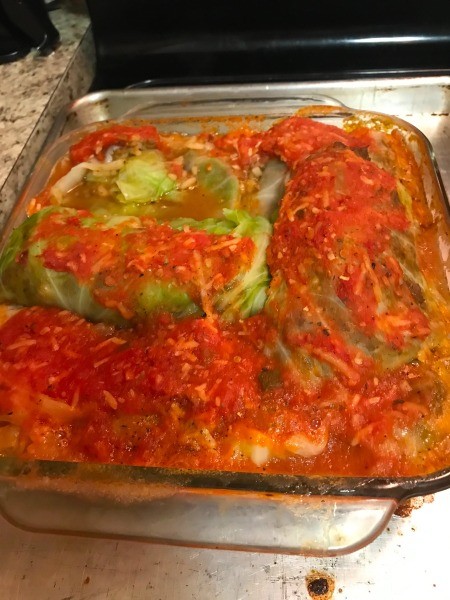 A pan of cabbage rolls covered in tomato sauce.