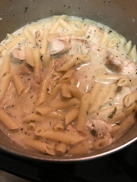 Adding the chicken to the pasta and sauce.