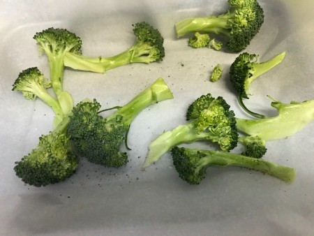 Pieces of broccoli on a baking sheet.