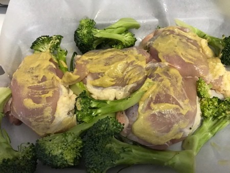 Covering the chicken thighs in dijon mustard.
