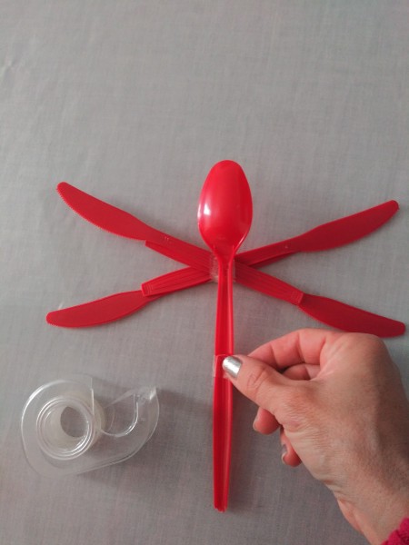 Adding the bottom of a spoon onto another spoon to make the dragonfly body.
