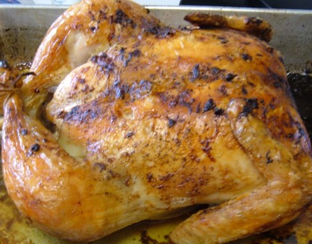 A roasted chicken in a roasting pan.