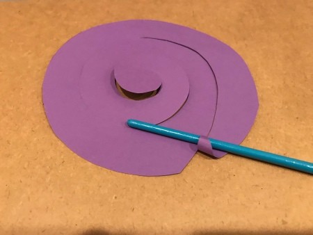 Rolling the paper around a paintbrush handle.