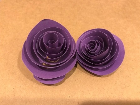 Creating two flower shapes out of purple paper.