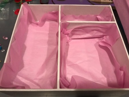 Lining the inside of a box with pink tissue paper.