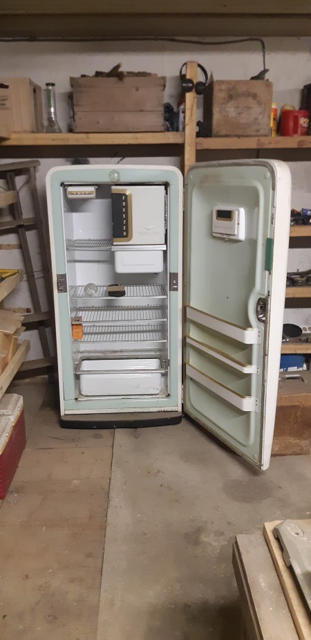 An old white refrigerator with the door open.