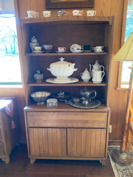 A wooden hutch with china and decorative servingware.