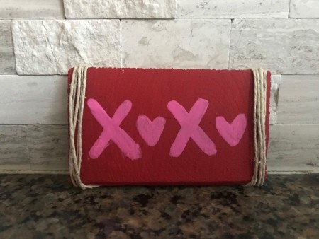 Cute Mini XOXO Wood Sign - sign resting against a wall