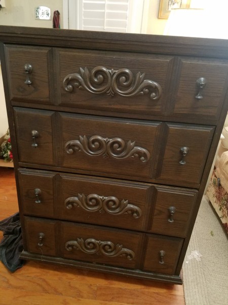 A chest of drawers with ornate metal handles.